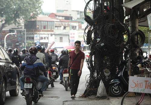 Không chỉ mắc chằng chịt trên những chiếc cột xiêu vẹo các bó dây điện, cáp viễn thông còn thõng xuống đường, nằm la liệt trên vỉa hè ở Hà Nội gây mất mỹ quan và nguy hiểm cho người qua lại.
