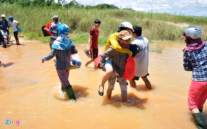 Do không thể đưa ghe vào sát bờ, người dân phải xắn quần tận gối lội bì bõm trong nước lũ để lên ghe qua sông Trà. 