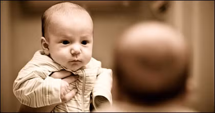 Khi cùng bé nhìn vào gương, bé chưa chắc đã hiểu được hình ảnh trong gương là cái gì. Nhưng điều đó không sao. Bé thích nhìn vào mặt người và đây là cách để bé cảm thấy gần gũi và riêng tư với chính mình. (Ảnh: Parents)