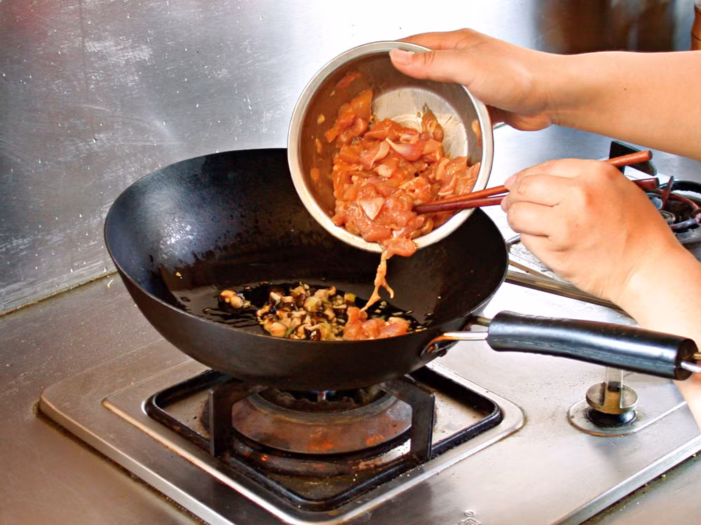 Làm nóng chảo rồi cho dầu vào. Phi tỏi và tỏi tây đã băm cho thơm rồi cho thịt gà vào rang. Nêm nếm thêm một chút xì dầu và rượu rồi rắc thêm một chút hạt tiêu cho tăng thêm hương vị.