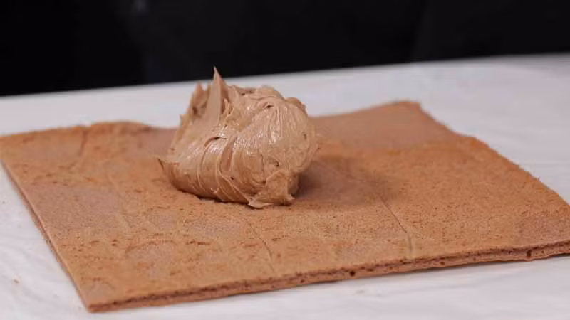 Trải cốt bánh lên một lớp giấy, phết một lớp kem lên trên rồi khéo léo cuốn chặt lại sao cho phần cốt bánh không bị vỡ.