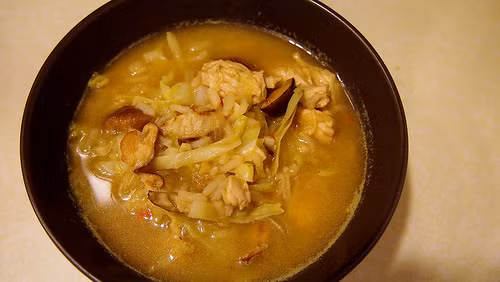 Cho ớt thái hạt lựu, tỏi, gừng vào xào tiếp khoảng 5 phút nữa cho thơm và mềm. Tiếp theo cho vỏ chanh, thịt gà và nước dùng gà vào đun sôi lên tiếp khoảng 15 phút nữa cho thịt gà chín. 