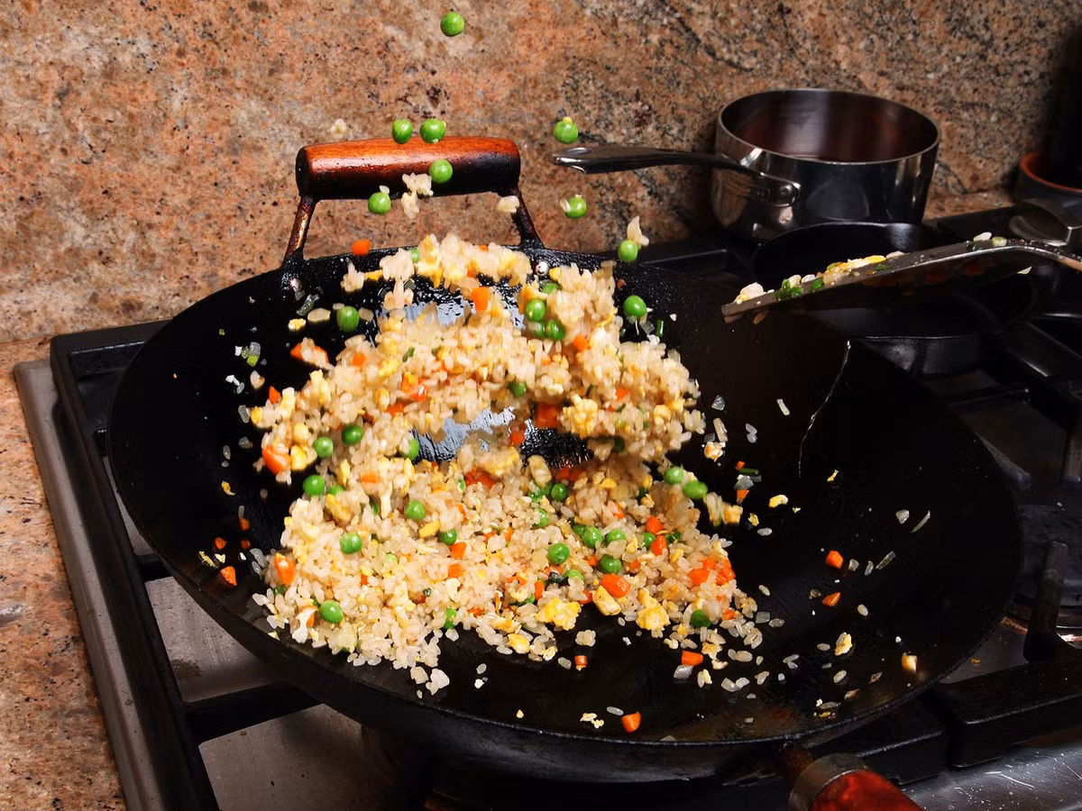 Món cơm rang không thể hoàn chỉnh nếu thiếu màu xanh của hành, đậu hay bất cứ thứ gì màu xanh. Và đừng quên trổ tài hất chảo trên bếp để món ăn được tơi xốp và đều gia vị. 