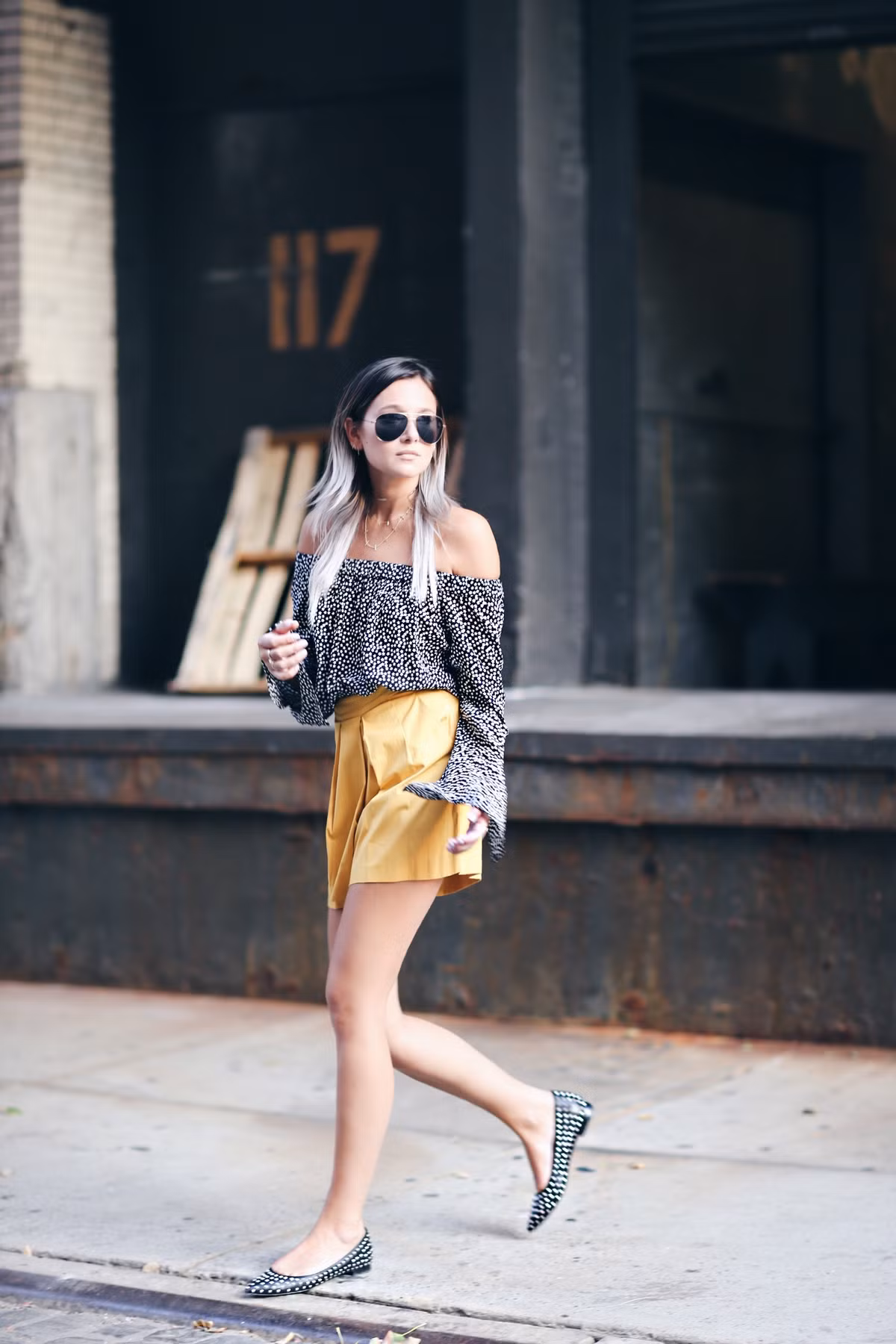 Áo trễ vai họa tiết đen trắng kết hợp với quần sooc màu vàng, không chói lóa mà vẫn bừng sáng. Đừng quên một đôi giày cùng tông quần hoặc tông áo.