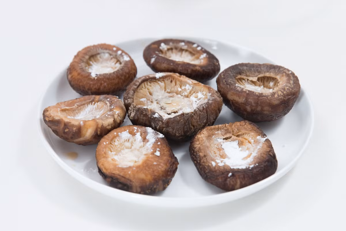 Rắc một chút bột bắp lên trên nấm rồi nhồi thịt lên trên, bột bắp sẽ giữ không cho thịt rơi ra khỏi mũ nấm. 