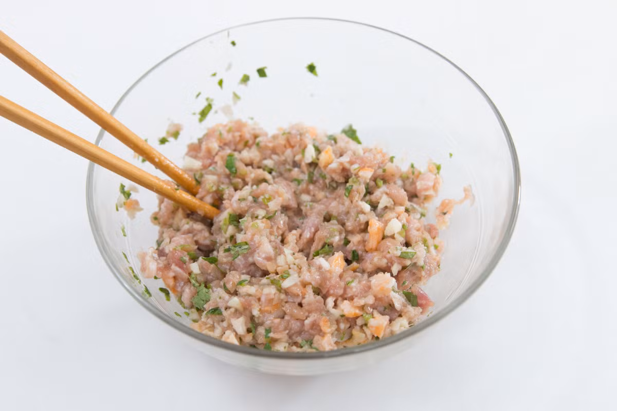 Trộn thịt lợn với lòng trắng trứng, một chút dầu ăn, nước tương, đường, dầu mè, bột bắp, hạt tiêu và để khoảng 20 phút cho ngấm gia vị. Tiếp đó cho củ năng, tỏi, tôm khô, rau mùi vào và trộn đều.