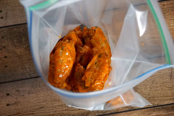 Vớt gà ra để nguội rồi cho vào túi nilong để vào ngăn đã tủ lạnh qua đêm. Khi để trong ngăn đá, lớp da gà ngoài cùng sẽ bị vỡ và nước ngọt từ bên trong sẽ bị rút hết ra ngoài. Đây chính là bí quyết để cánh gà giòn. Qua ngày hôm sau cánh gà sẽ khô hết mức có thể. 