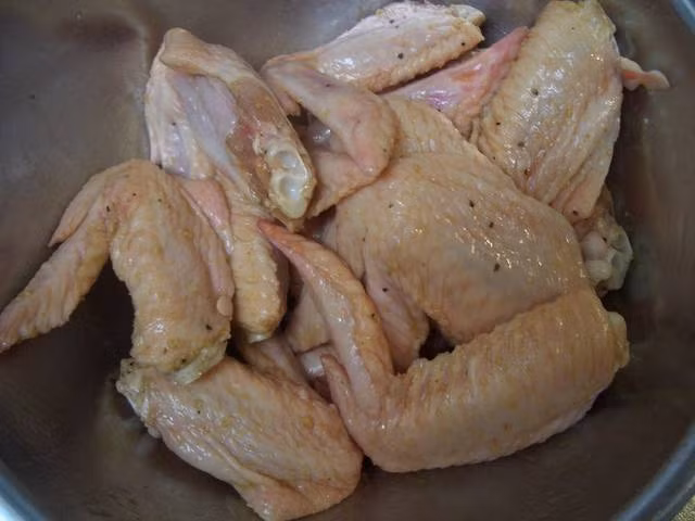 Ướp cánh gà với muối, tiêu, rượu, xì dầu, bột nước dùng gà và dầu mè khoảng nửa ngày cho ngấm đều. 