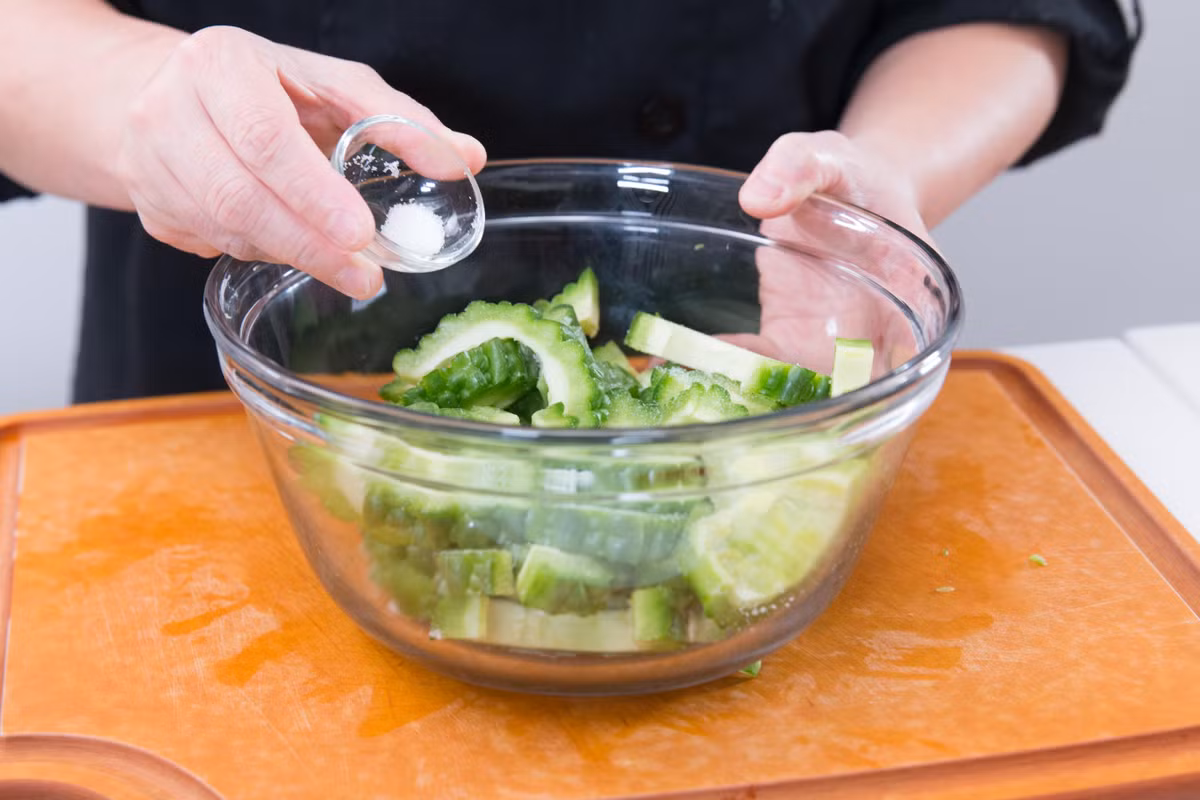 Mướp đắng cắt đôi theo chiều dọc, bỏ hạt và cắt thành miếng dày khoảng 1cm. Ớt chuông thái sợi dày, trứng bắc thảo và trứng muối sau khi luộc bổ thành múi cau. 