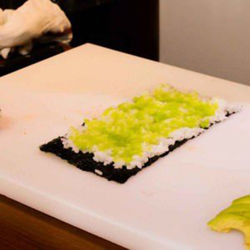 Trải một lớp cơm dùng để cuốn sushi khoảng 80g lên nửa lá rong biển, chừa lại khoảng 1cm ở đầu lá.