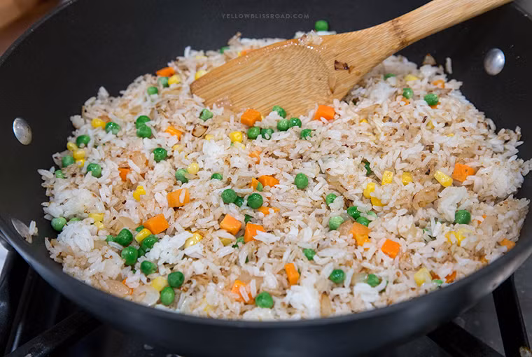 Tiếp theo cho cà rốt và dứa thái hạt lựu cùng đậu hà lan vào đảo đều cùng cơm rang cho chín thì nêm gia vị cho vừa ăn.