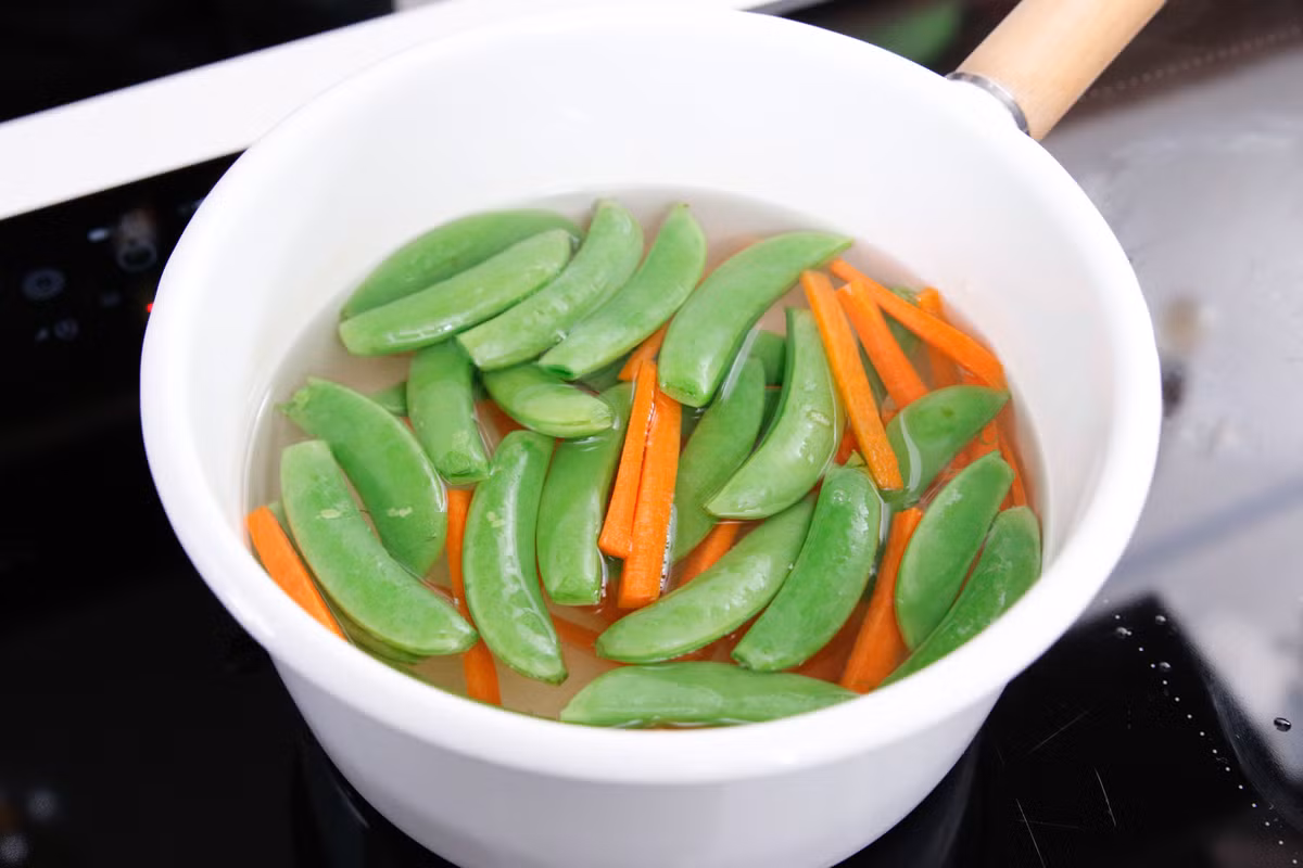 Đun sôi nước rồi cho đậu Hà Lan và cà rốt vào chần qua cho mềm. 