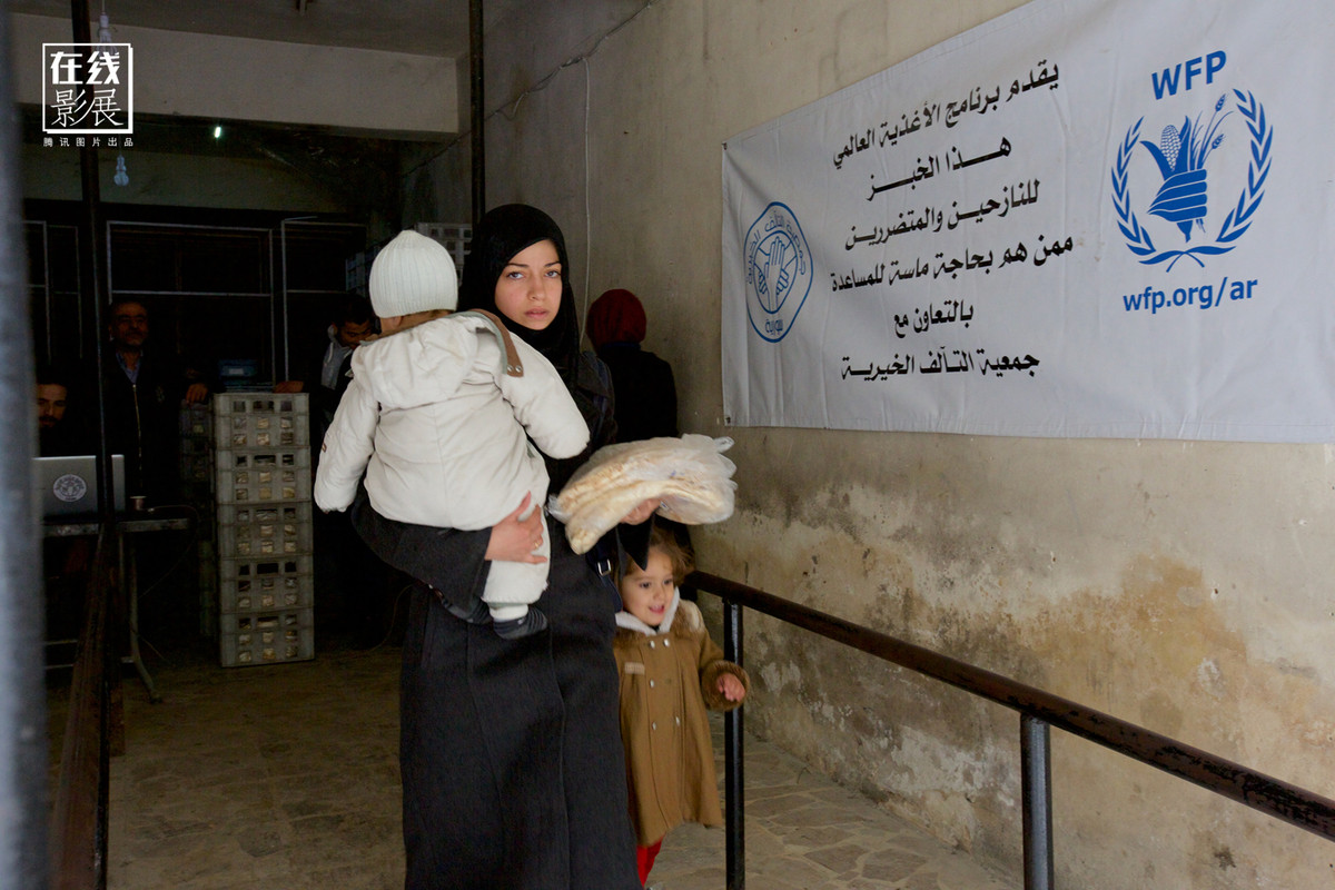 Bà mẹ trẻ đang cùng hai con tới điểm nhận đồ ăn viện trợ, quá trình tái thiết diễn ra khá chậm ngay tại trung tâm Aleppo khi chiến sự vẫn tiếp diễn xung quanh khu vực này.