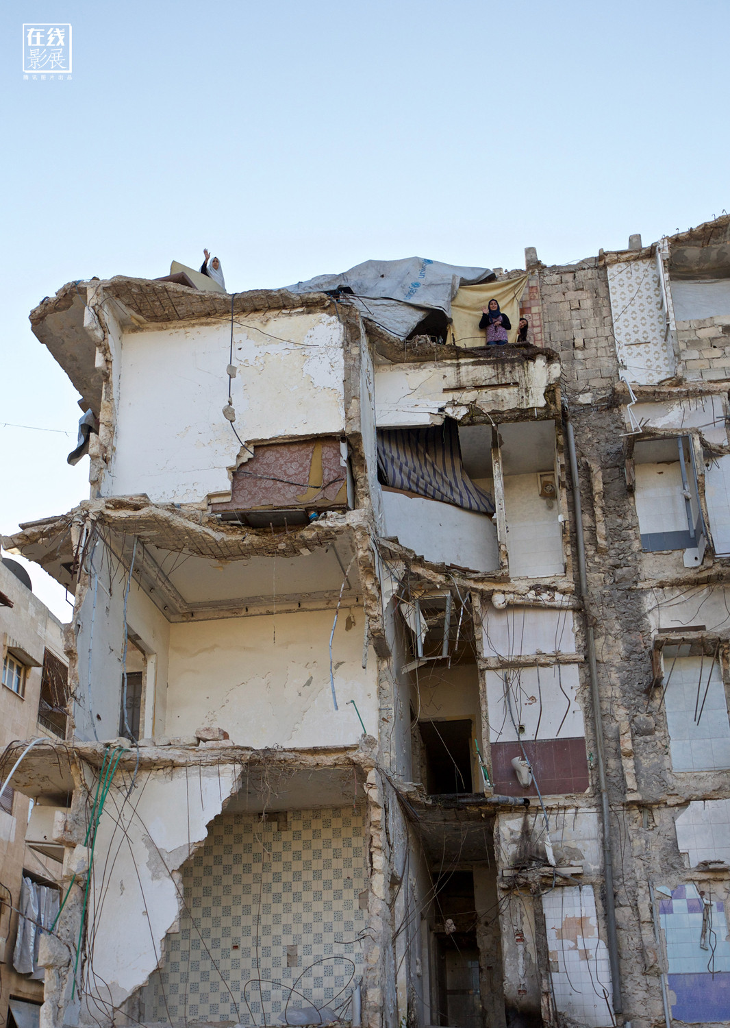 Bé gái đứng trên bậc thang của một tòa nhà đổ nát, nơi trước kia từng có nhà của bé.