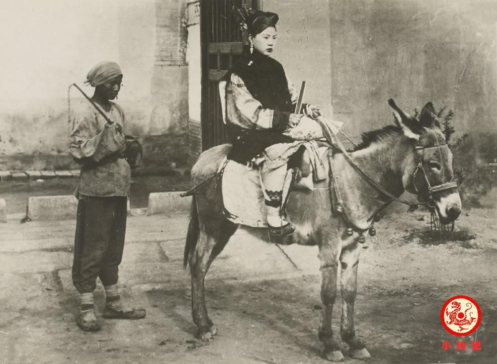 Người phụ nữ thuộc gia đình giàu có thời nhà Thanh ngồi trên lưng lừa. Một người hầu đang đứng ở phía sau. (Nguồn ảnh Sohu).