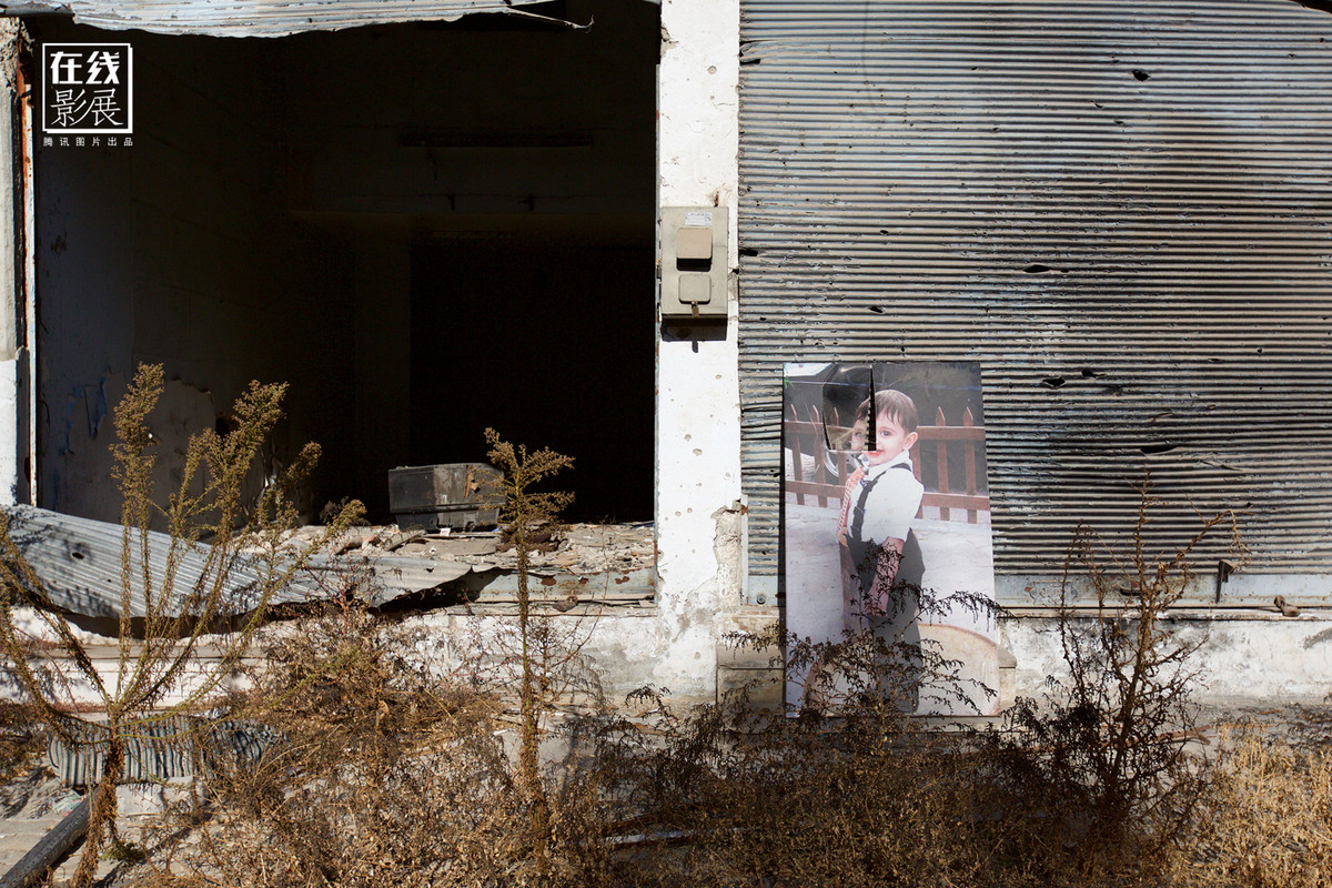 Bức ảnh một em bé đã chết được dựng phía ngoài một ngôi nhà ở Homs. Thông thường cha mẹ các em bé không may mắn này sẽ để ảnh con mình bên ngoài nhà.