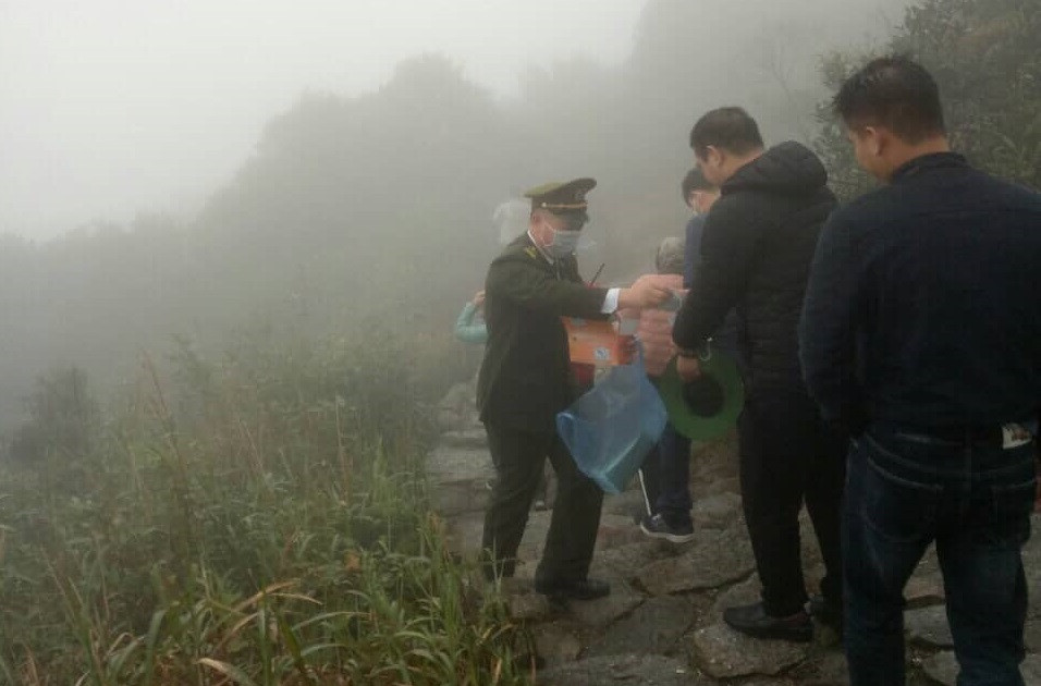 Cán bộ Ban quản lý phát khẩu trang miễn phí cho du khách trên đường lên Chùa Đồng Yên Tử.