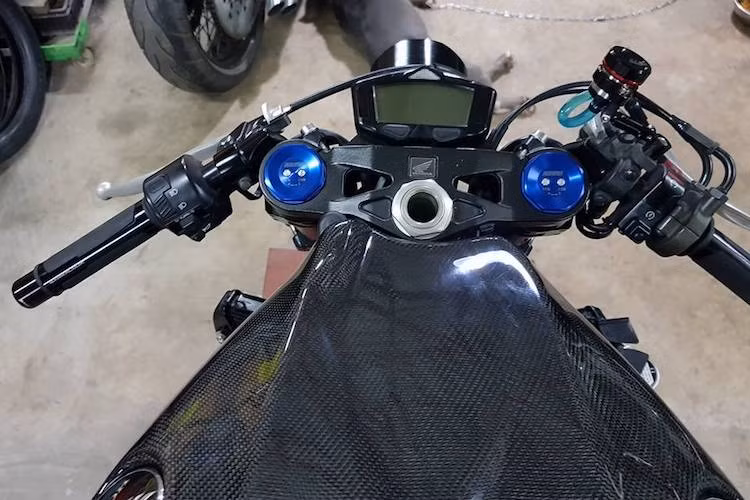 Tay lái dạng clip-on của CBR1000RR nguyên bản được xưởng độ Việt giữ nguyên, hai đầu là bao tay Barracuda. Thay cho đồng hồ điện tử nguyên bản của xe là loại đồng hồ mini Koso DB-03 với kích thước nhỏ gọn hơn. Ở bên dưới chảng ba, ốp bình xăng nguyên bản của CBR1000RR đã được thay thế bằng ốp sợi carbon.