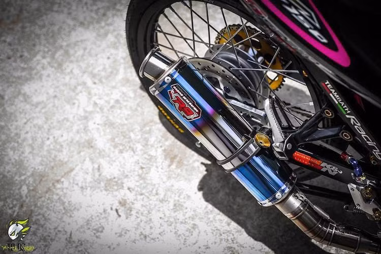 Nằm ở khu vực giữa xe nổi bật với những con ốc chén Trusty màu vàng nổi bật. Hệ thống xả của chiếc xe gồm cổ pô "hàng thửa" và cây pô R9 ánh xanh giả màu titan, phô diễn tiếng nổ của động cơ ấn tượng hơn. Cuối cùng, biển số đẹp tứ quý 6 cũng khẳng định độ "chơi" của chủ xe.