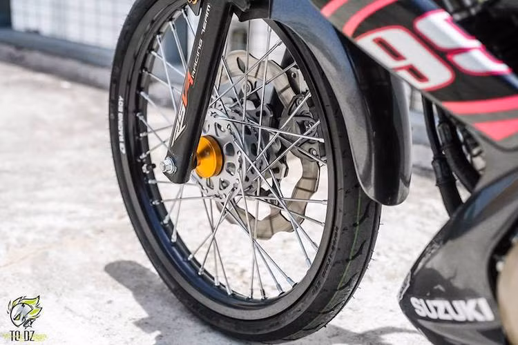 Dòng xe côn tay Satria 150 hay Raider 150 vốn nổi tiếng bởi thiết kế mâm đúc 5 cây "xương cá" độc đáo. Tuy nhiên trên bản độ này, chủ xe đã thay cặp mâm nguyên bản bằng bánh căm với niềng nhôm Racing Boy. Hệ thống phanh trước của chiếc xe cũng được độ lại bằng heo Brembo 2 pis đối xứng và đĩa Galfer.