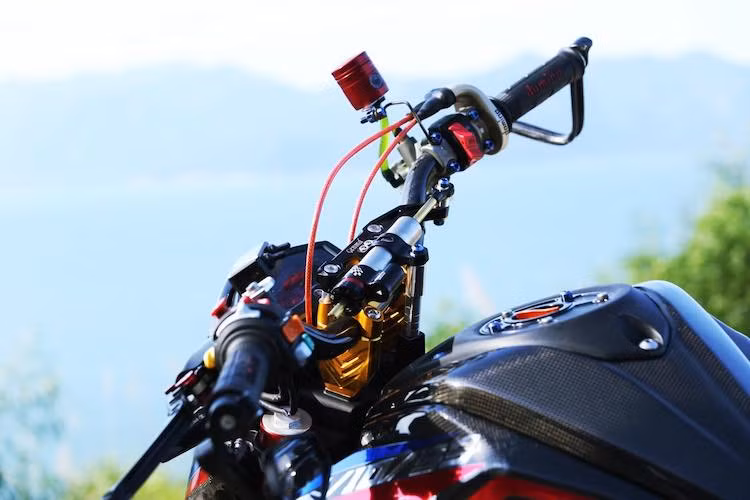 Ở phía trên tay lái, chủ xe đã thay ghi-đông nguyên bản của chiếc xe côn tay TFX150 bằng ghi-đông sợi carbon siêu nhẹ. Trên tay lái của xe cũng là hàng loạt các "đồ chơi" như cùm công tắc rút gọn, bao tay Domino, cùm ga Domino, trợ lực Matris và gù ghi-đông Genma. Ở dưới bình xăng là nắp xăng đóng mở nhanh kiểu xe đua của Ducabike.