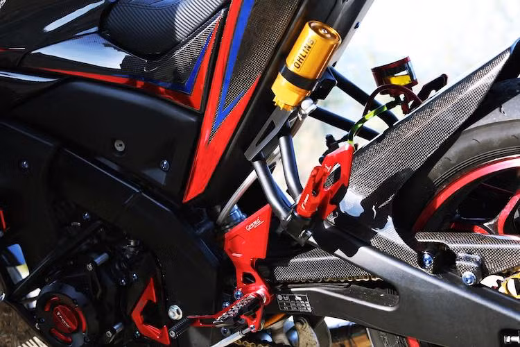 Để chân sau của Rizoma cùng dàn để chân trước của Genma bằng nhôm màu đỏ khiến cho chiếc TFX150 trở nên nổi bật hơn. Trong khi đó, cây phuộc Ohlins bình dầu rời tăng độ ổn định cho đuôi xe khi vận hành. Chắn xích và dè con nguyên bản cũng đã được chủ xe độ lại bằng loại làm từ sợi carbon.