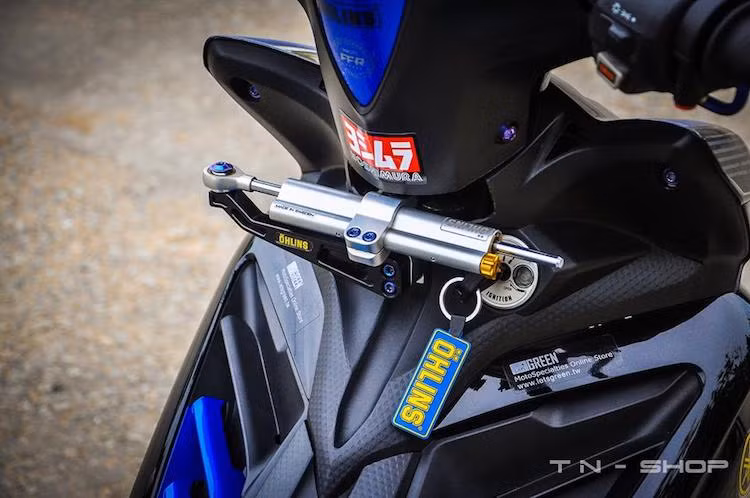 Cụm đồng hồ nguyên bản trên tay lái của chiếc xe đã được thay bằng đồng hồ Koso điện tử dành cho Exciter 2009, nhưng đã được chế mủ nhựa đầu để vừa với phiên bản 2011. Nằm bên dưới cổ xe là cây trợ lực Ohlins tem khắc cùng núm tăng chỉnh và pad bắt nhôm CNC.