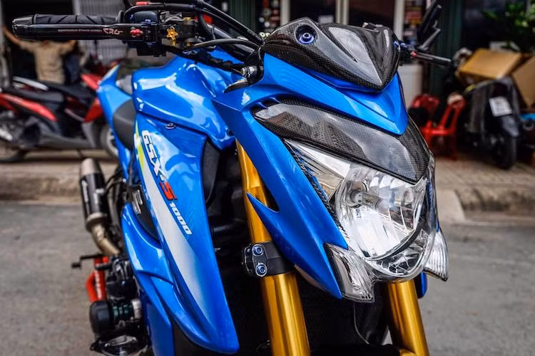 Ở phía trước, bộ ốp đầu đèn và chắn gió bằng sợi carbon đã khiến GSX-S1000 trở nên thể thao và dữ dằn hơn. Cụm ghi-đông nguyên bản của chiếc xe cũng đã được thay bằng ghi-đông làm từ sợi carbon của hãng Driven tới từ Mỹ, giúp giảm trọng lượng so với tay lái nhôm nguyên bản.