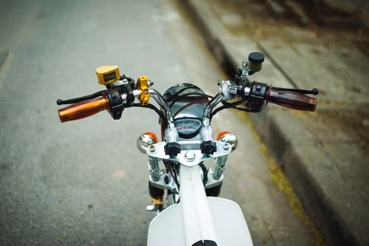 Ghi-đông nguyên bản của Chaly đã được MTK thay thế bằng tay lái clip-on có thể gập lên xuống, được nhập từ Thái Lan. Thiết kế tay lái này vốn được Honda dành cho dòng xe Ape. Ở phía trên tay lái là một số "đồ chơi" đơn giản như bình dầu Rizoma và bao tay phong cách Posh.