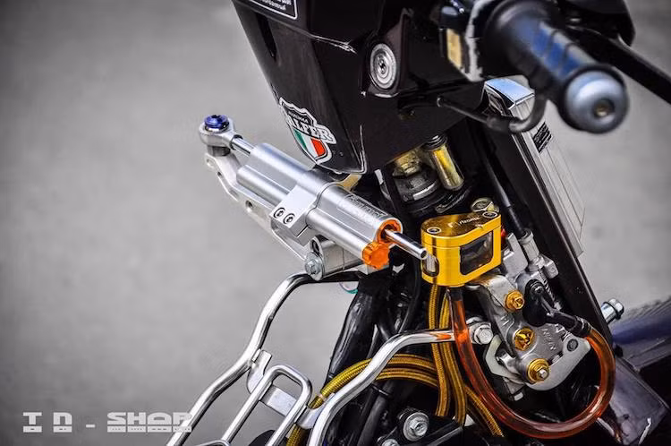 Pen Honda Vision đã được sử dụng cho hệ thống phanh trước với ưu điểm là nhỏ gọn, có thể giấu bên dưới cổ xe. Dầu phanh được chứa trong bình dầu Rizoma, bên cạnh là cây trợ lực Ohlins giữ cho phần đầu xe ổn định hơn ở tốc độ cao.