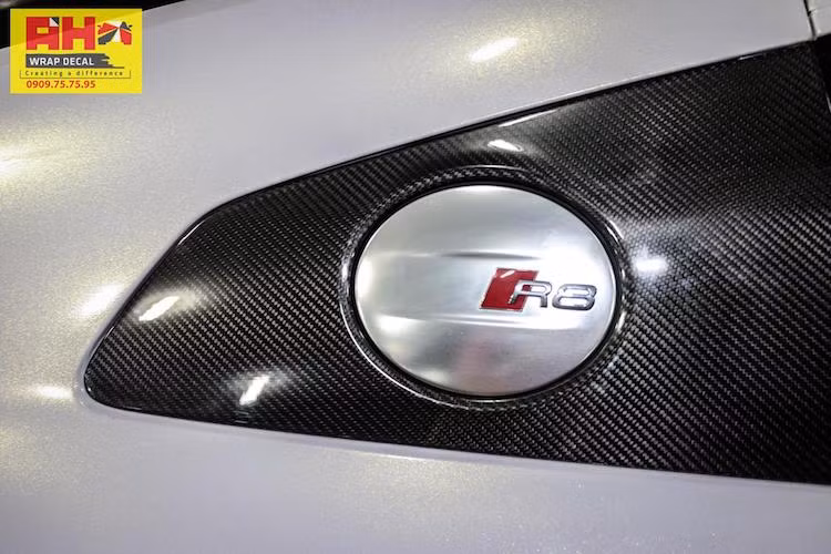 Dưới ánh sáng chiếu theo nhiều góc độ khác nhau, hiệu ứng ánh ngọc của lớp decal mới lộ rõ. Một số chi tiết bằng sợi carbon nguyên bản trên R8 như ốp gương chiếu hậu, các tấm ốp 2 bên khe hút gió và cánh đuôi của xe không được dán decal, để lộ lớp sợi carbon đen tương phản với màu thân xe trắng.