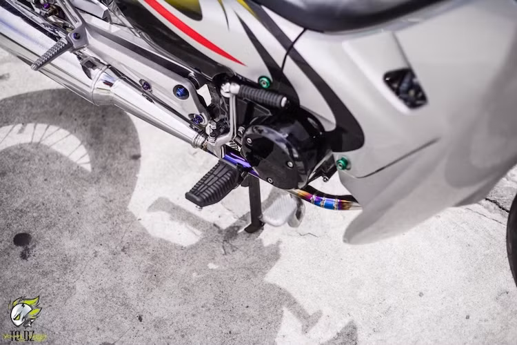 Khu vực động cơ càng trở nên ấn tượng với cổ pô "hàng thửa" từ vật liệu titan, dẫn khí thải ra cây pô nguyên bản nhưng được móc lại để cho âm thanh trầm ấm hơn. Những biker am hiểu về xe cũng có thể dễ dàng nhận ra phần gác chân đã được thay từ Yamaha Exciter.