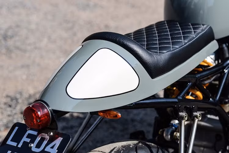 Ở phía sau, xưởng độ xe đã sửa đổi lại phần khung phụ của chiếc 1000SS để lắp lên phần đuôi mang phong cách cafe racer, kèm theo chiếc yên bọc da chần chỉ vân con thoi cổ điển. So với 750SS nguyên bản, phần đuôi này có thiết kế tinh tế, nhỏ gọn hơn và được tích hợp đầy đủ xi-nhan cùng đèn hậu.