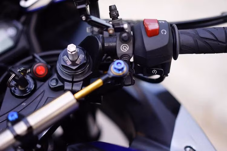 Trên bản độ này, giảm xóc trước dạng ống lồng của R3 chỉ còn giữ lại bộ vỏ khi toàn bộ phần ruột bên trong đã được nâng cấp bằng kit độ của Ohlins, kèm theo ốc đầu với khả năng điều chỉnh độ nhún/nảy của phuộc. Nằm chính giữa chảng ba của xe còn có thêm cây trợ lực Matris để khiến phần đầu xe ổn định hơn.