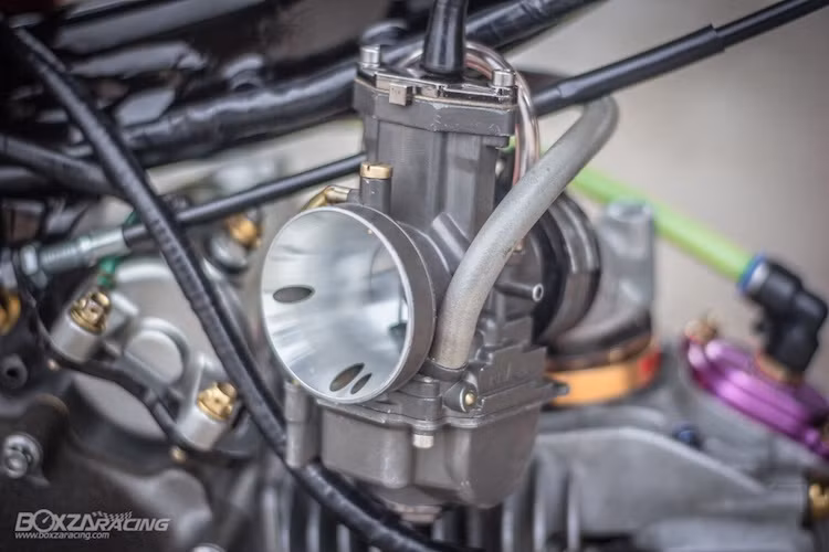 "Nuôi ăn" cho khối động cơ mạnh mẽ này là bộ chế hòa khí Keihin với họng vuông 32 mm. Ngoài ra, dung tích bình xăng của xe cũng được nâng lên gấp đôi so với nguyên bản với bình nhôm "hàng thửa" chiếm trọn phần dưới yên sau. Đương nhiên, với động cơ mạnh mẽ, chủ xe cũng phải gia cố lại bộ khung Wave.