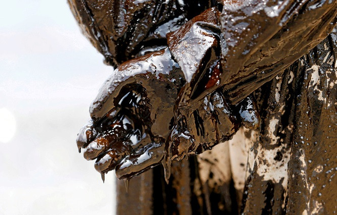 13. Một thành viên của lực lượng bảo vệ bờ biển Sri Lanka bị dầu bao phủ sau thi làm nhiệm vụ khắc phục một sự cố tràn dầu tại một bãi biển ở Uswetakeiyawa.