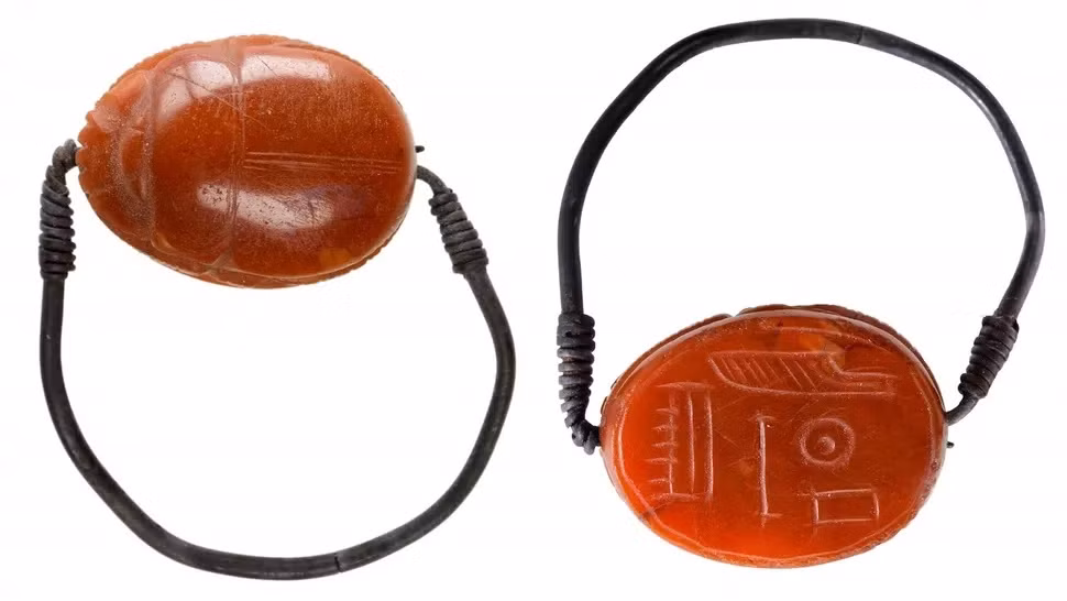 "Người phụ nữ la hét" đeo 2 chiếc nhẫn bằng bạc chạm khắc hình bọ hung. Trên đầu bà là một bộ tóc giả được tết qua loa.