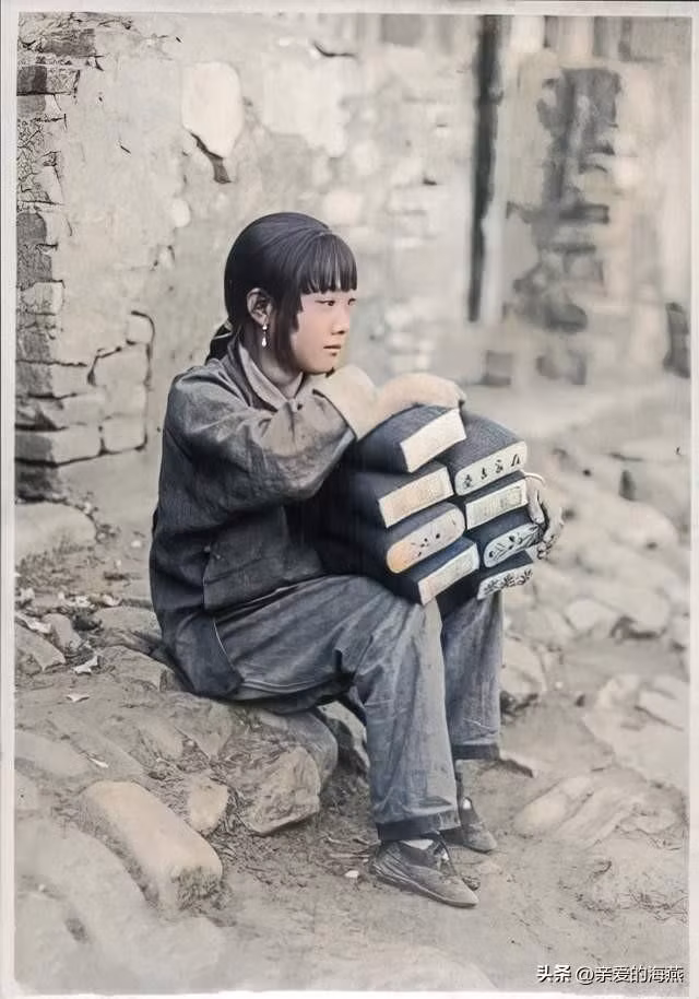 Một bé gái khoảng 10 tuổi ngồi bán những chiếc gối tại một góc đường.