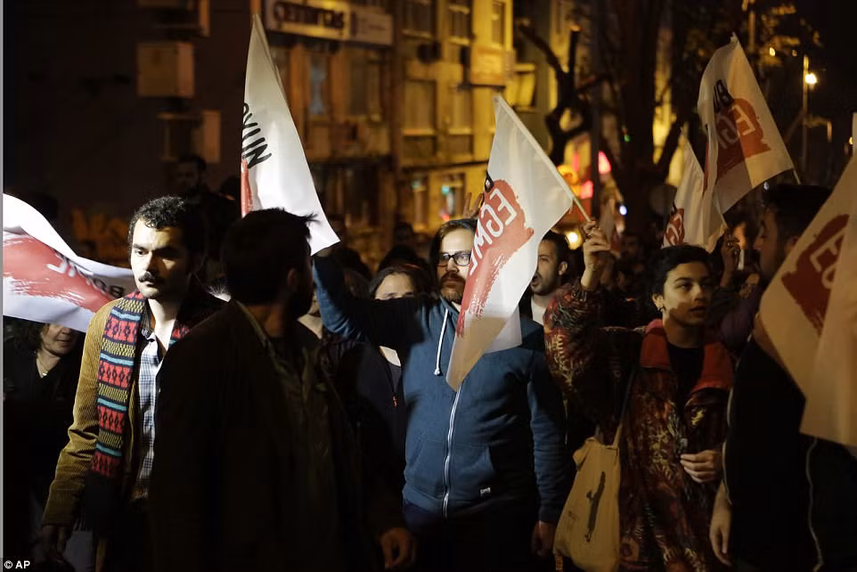 Đám đông người biểu tình giơ cao cờ in dòng chữ "Không".