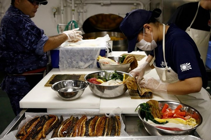 Một đầu bếp nữ đang chuẩn bị món sushi trong bếp ăn của tàu Kaga.