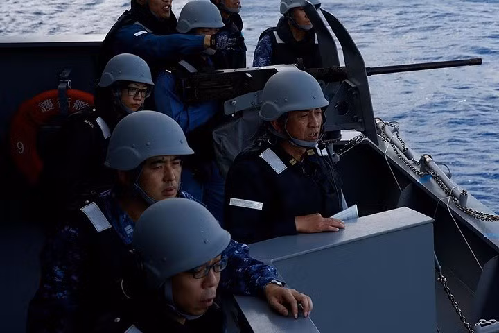 Một nữ thủy thủ Nhật Bản (đeo kính, bên trái) đang theo dõi diễn tập bắn đạn thật bằng súng máy 12,7mm của tàu Kaga.