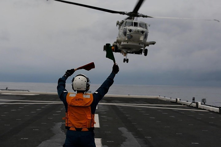 Nữ hạ sĩ quan Akiko Ihara hướng dẫn máy bay trực thăng SH-60K Sea Hawk hạ cánh lên boong tàu.