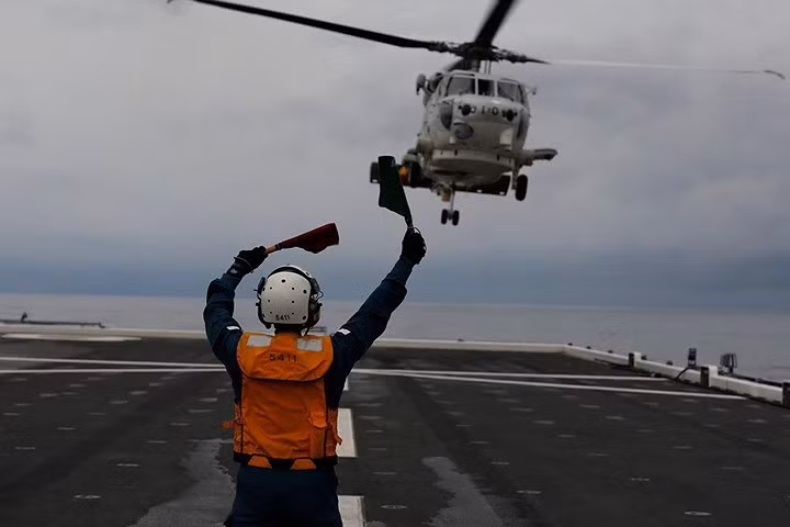 Nữ hạ sĩ quan Akiko Ihara hướng dẫn máy bay trực thăng SH-60K Sea Hawk hạ cánh lên boong tàu.