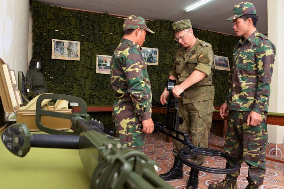 Trong ảnh là một công binh Nga đang hướng dẫn các binh sĩ Lào sử dụng thiết bị dò mìn cầm tay thế hệ mới MG-1. Nguồn ảnh: Bộ Quốc phòng Nga.