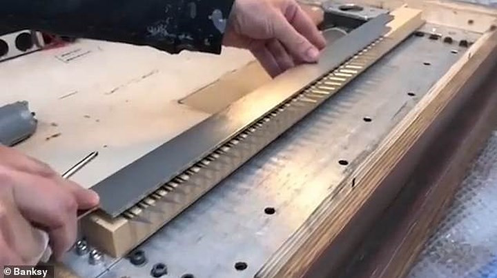 Đoạn clip do họa sỹ Banksy đăng tải trên trang Instagram mà ông xóa ngay sau đó cho thấy, họa sỹ này đã cài một thiết bị cắt giấy vào bức tranh, được điều khiển bằng thiết bị từ xa. Ảnh: Banksy.