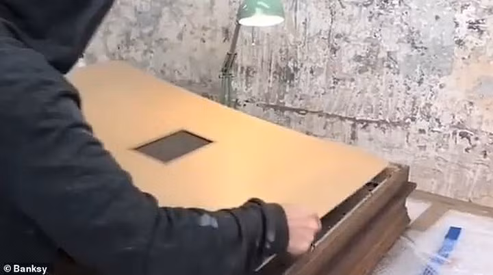 Banksy được cho là đeo chiếc mặt nạ màu đen khi lắp thiết bị này vào sau bức tranh. Ảnh: Banksy.