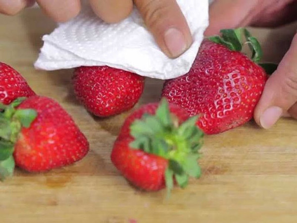 Dùng khăn khô hoặc giấy thấm lau dâu tây nhẹ nhàng, loại bỏ vi khuẩn trên bề mặt quả.