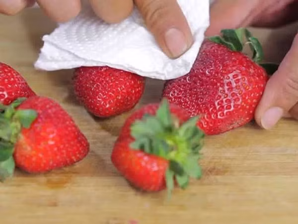 Dùng khăn khô hoặc giấy thấm lau dâu tây nhẹ nhàng, loại bỏ vi khuẩn trên bề mặt quả.