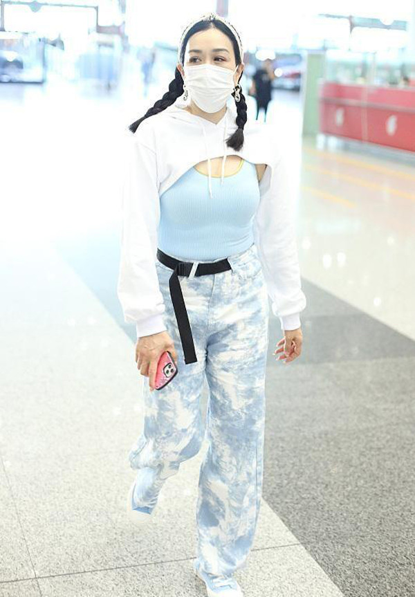 Chiếc áo gam màu trắng, có mũ tạo điểm nhấn, cổ polo, tay dáng dài song gần như không có tác dụng che chắn. Cô gái phải tận dụng chiếc áo hai dây xanh nhạt để không để lộ phần nhạy cảm.