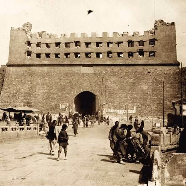 Dân thường và lính liên quân hiện diện bên ngoài một cổng thành.